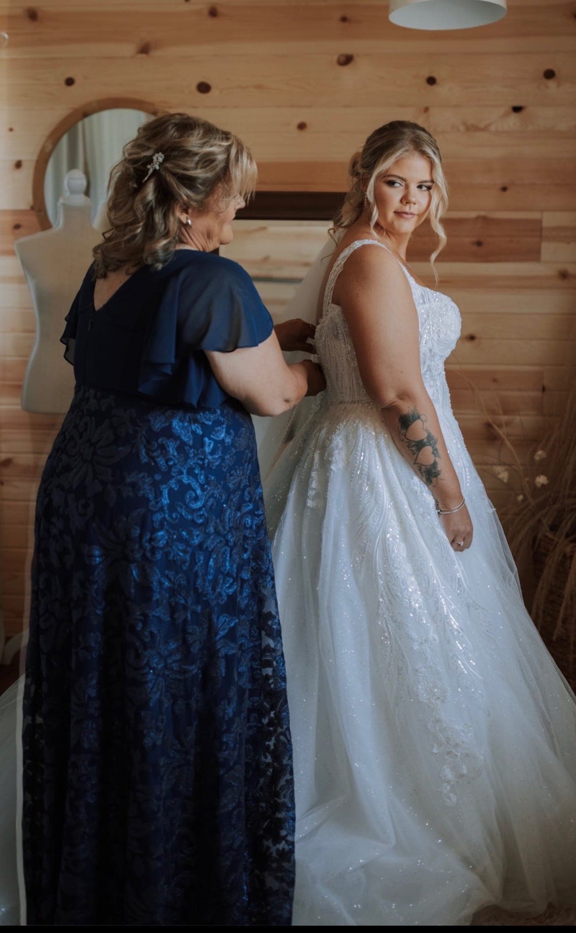 Mother of the bride fastening her daughter into a sparkling ballgown, photo by Kirkland Photography
