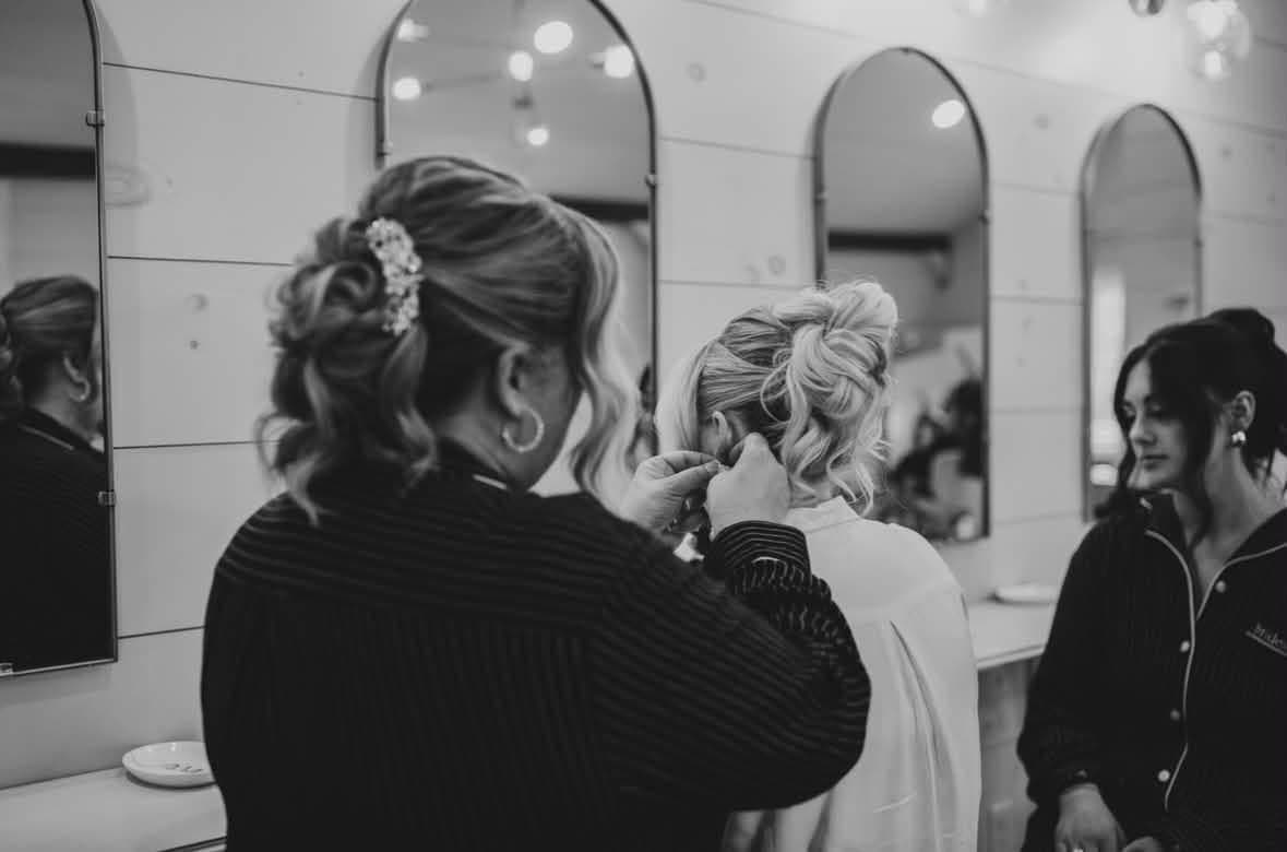 Lost Sheep stylist pinning a bride's updo at the salon mirrors on the wedding morning (B&W), photo by Kirkland Photography